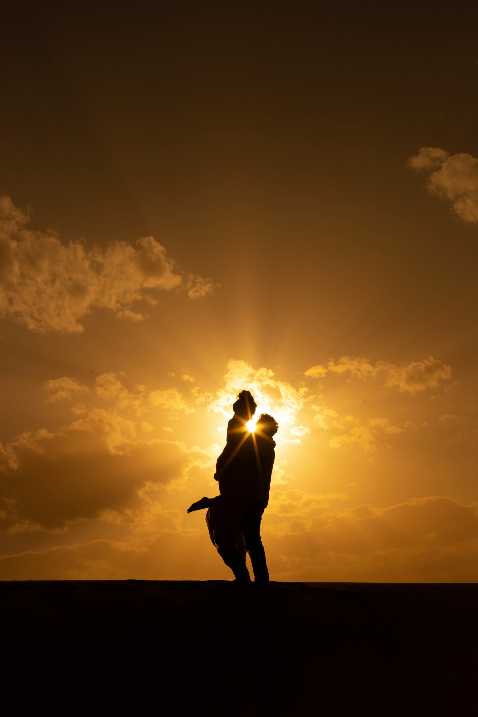 Morocco anniversary trip — couple embracing at Sahara desert sunset, Merzouga